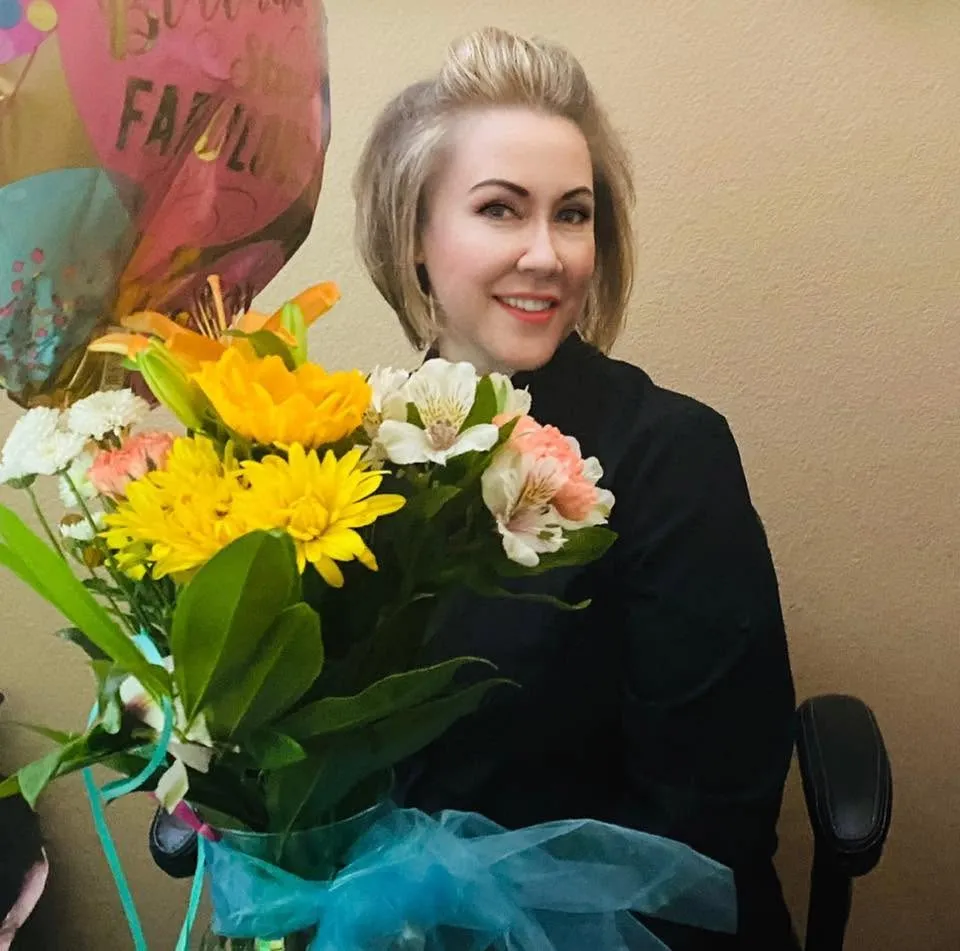 Dr. Hidy Stavarache smiling, holding a bouquet of flowers from a patient